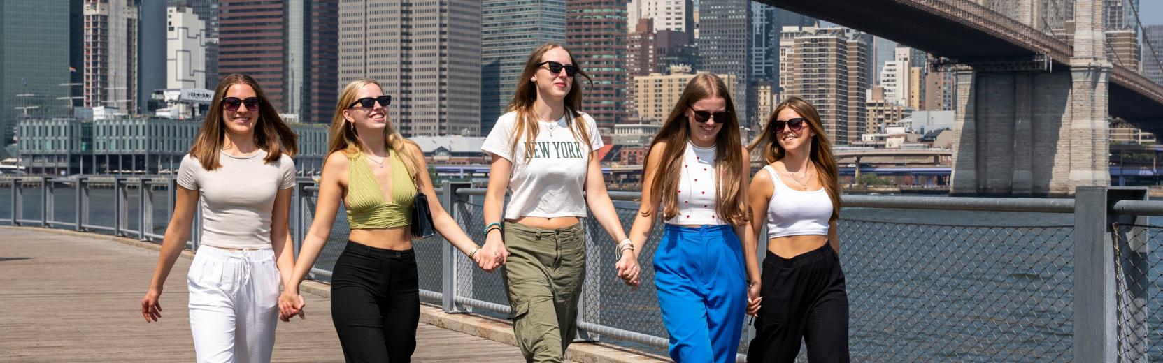 Un groupe d'au pairs se baladant à New York avec le pont de Brooklyn en arrière-plan.