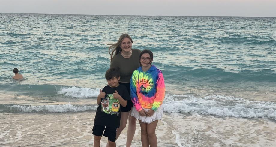 Laura, au pair, et ses enfants d’accueil s’enlacent au bord de l’océan