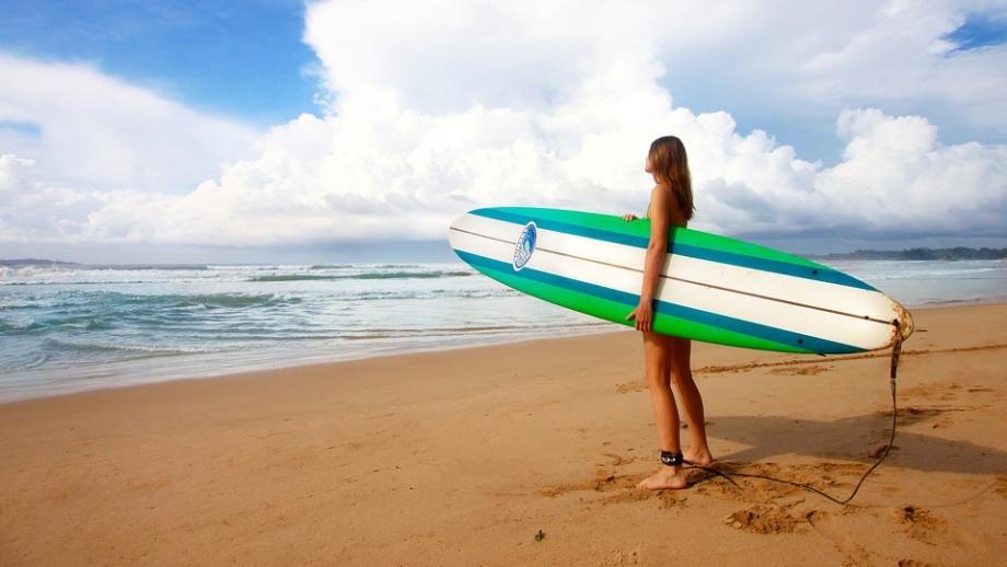 fille avec une planche de surf sur une plage