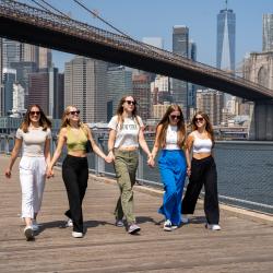 Un groupe d'au pairs se baladant à New York avec le pont de Brooklyn en arrière-plan.