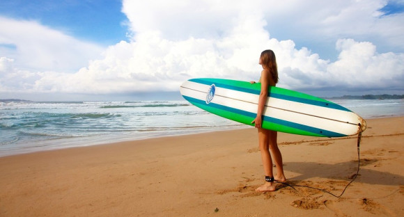 fille avec une planche de surf sur la plage